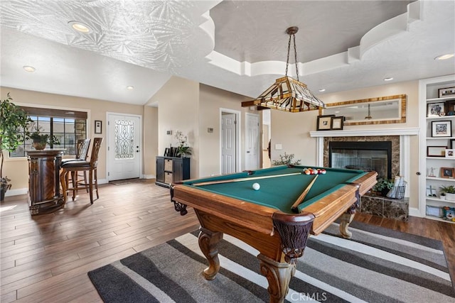 playroom featuring dark hardwood / wood-style floors, a fireplace, billiards, a tray ceiling, and built in shelves