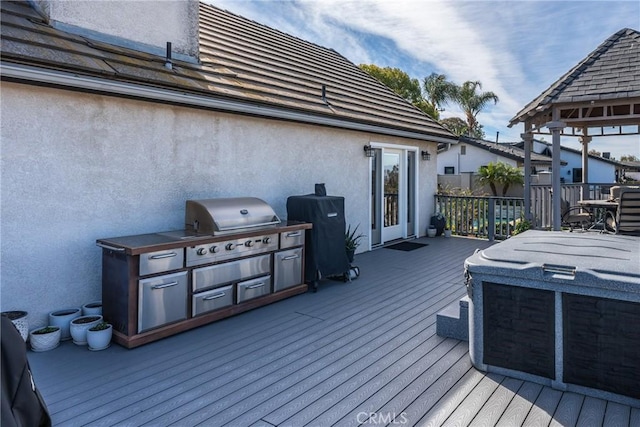 wooden terrace with an outdoor kitchen, grilling area, and a jacuzzi