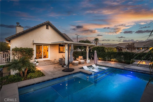 pool at dusk with a patio and a jacuzzi