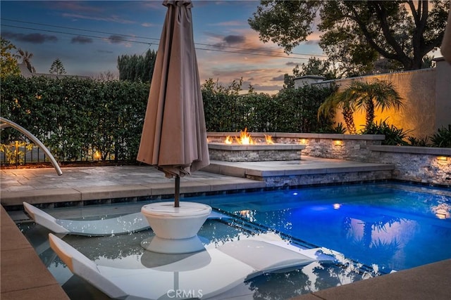 pool at dusk featuring a patio, a jacuzzi, and a fire pit