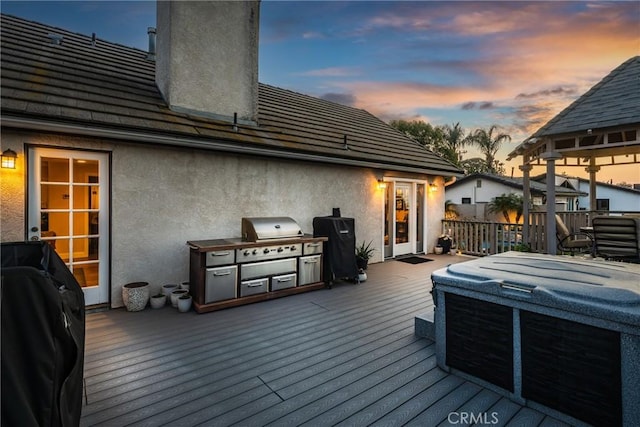 deck at dusk with a grill and a hot tub