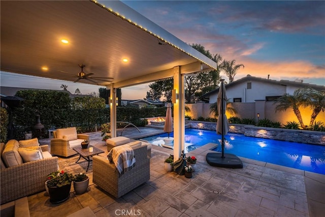 pool at dusk with a patio, outdoor lounge area, pool water feature, and ceiling fan