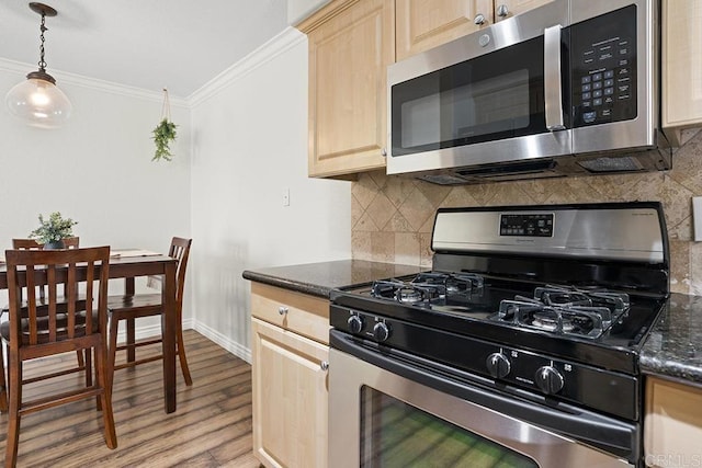 kitchen with stainless steel appliances, ornamental molding, light brown cabinets, and dark stone counters