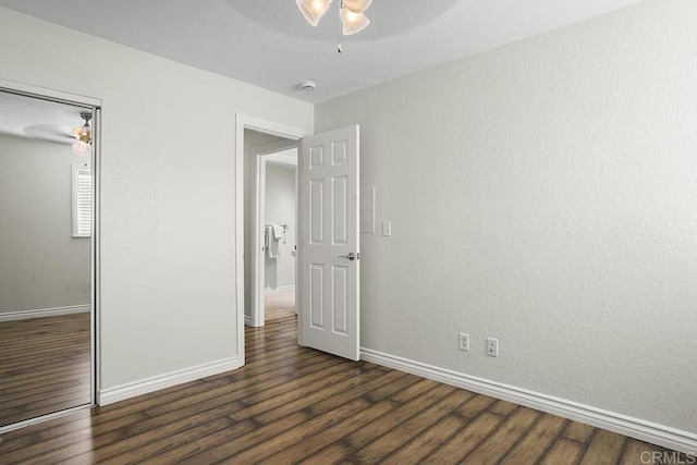 unfurnished bedroom with dark wood-type flooring, ceiling fan, and a closet