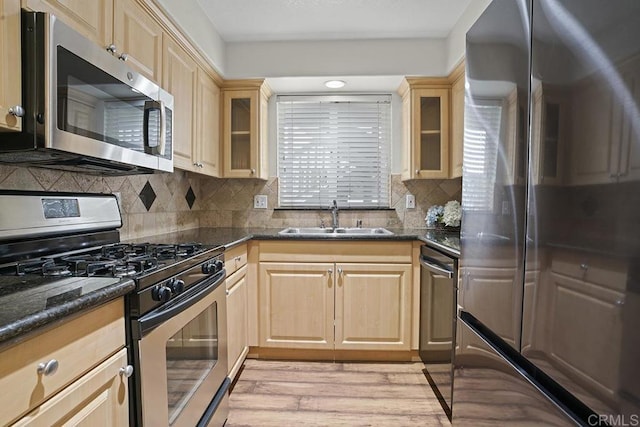 kitchen with sink, decorative backsplash, dark stone counters, stainless steel appliances, and light brown cabinets