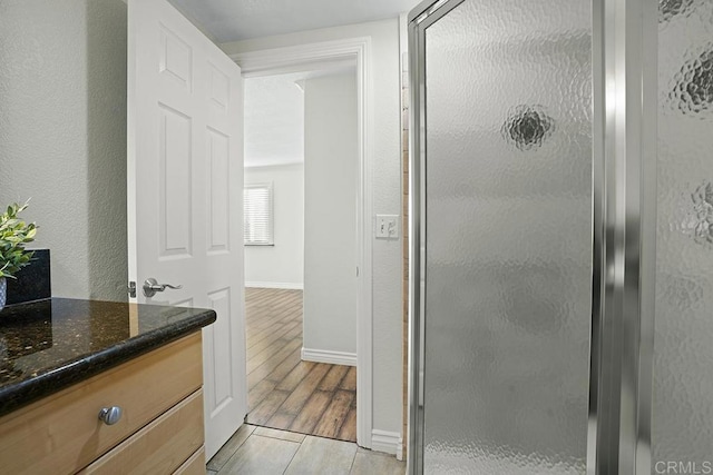 bathroom featuring a shower with door and vanity