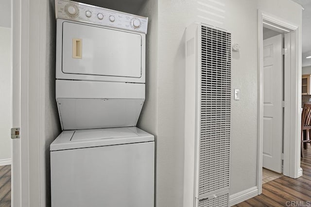 washroom with dark wood-type flooring and stacked washing maching and dryer