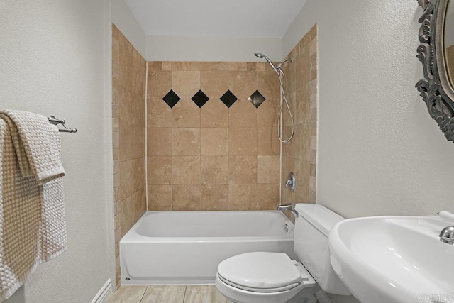 full bathroom featuring sink, tiled shower / bath combo, and toilet