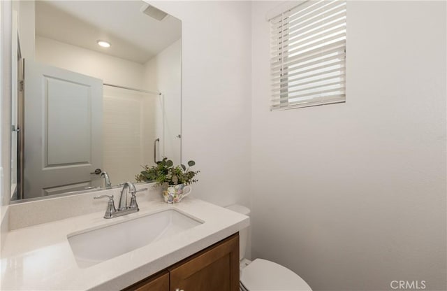 bathroom featuring vanity, walk in shower, and toilet