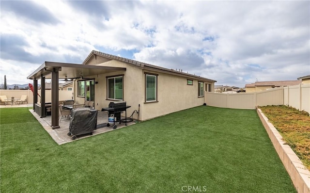 rear view of property with a yard, a patio area, and ceiling fan