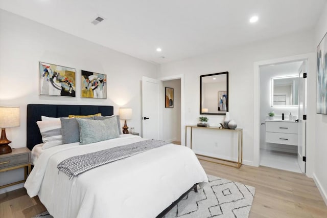 bedroom featuring connected bathroom and light hardwood / wood-style floors