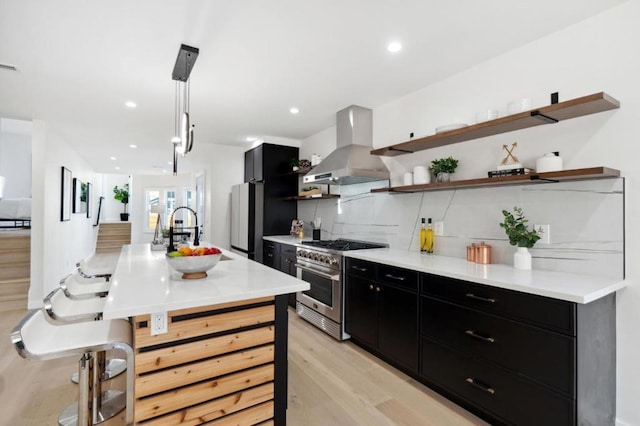 kitchen featuring pendant lighting, island range hood, tasteful backsplash, sink, and high end range