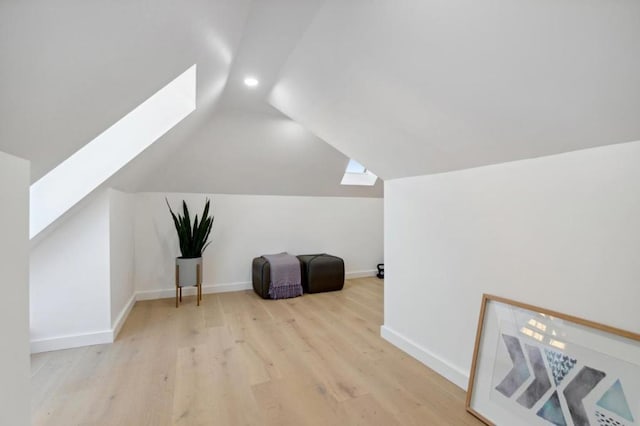 bonus room featuring lofted ceiling with skylight and light hardwood / wood-style flooring