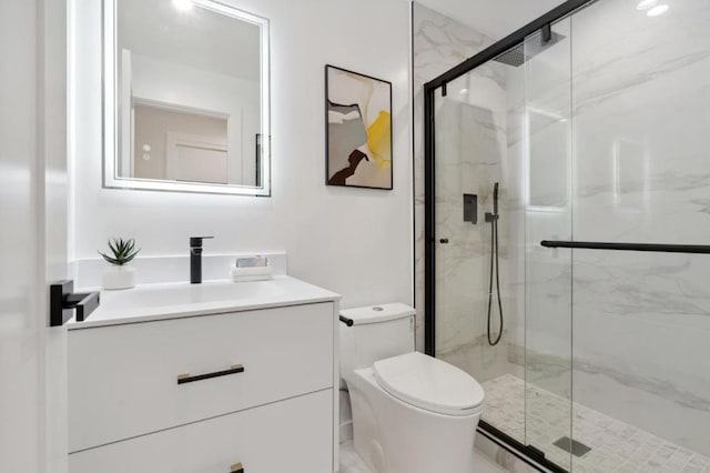 bathroom featuring vanity, a shower with shower door, and toilet