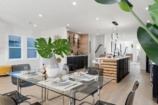 dining area featuring sink, light hardwood / wood-style flooring, and beverage cooler