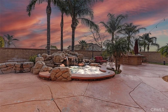 patio terrace at dusk featuring a bar