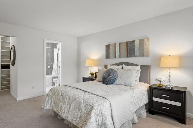 bedroom featuring a spacious closet, ensuite bath, light colored carpet, and a closet