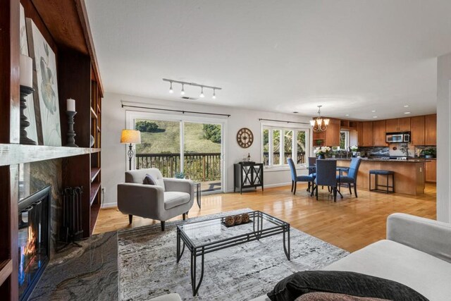 living room featuring light hardwood / wood-style flooring, a notable chandelier, a high end fireplace, and rail lighting