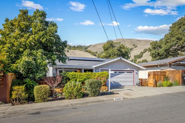 view of front facade featuring a garage, a mountain view, and solar panels