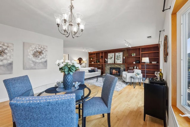 dining area with a fireplace, a chandelier, and light wood-type flooring