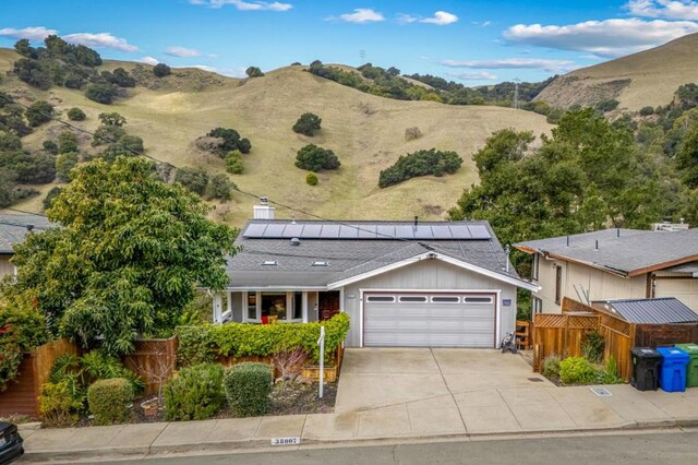 ranch-style house featuring a garage, a mountain view, and solar panels