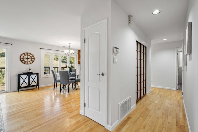 hallway featuring a chandelier and light wood-type flooring