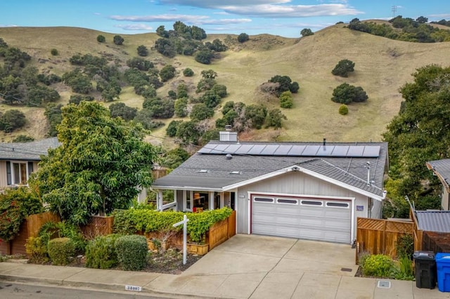 view of front of home with a garage, a mountain view, and solar panels