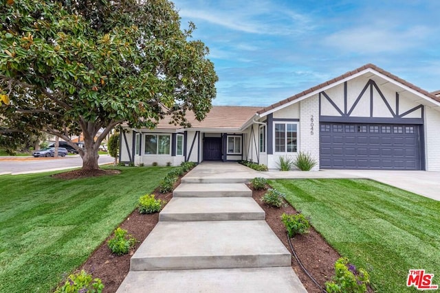 tudor house featuring a garage and a front lawn