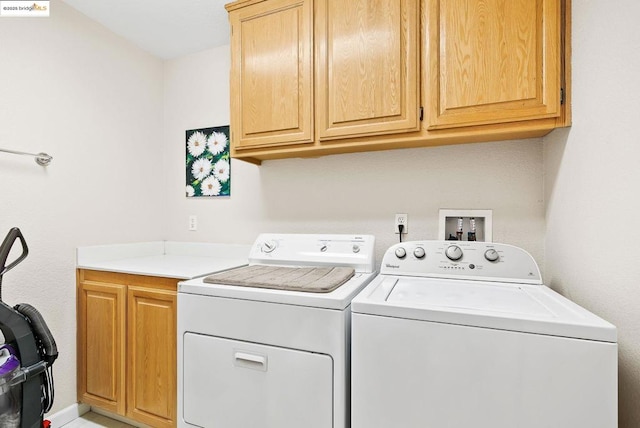 clothes washing area with cabinets and washing machine and clothes dryer