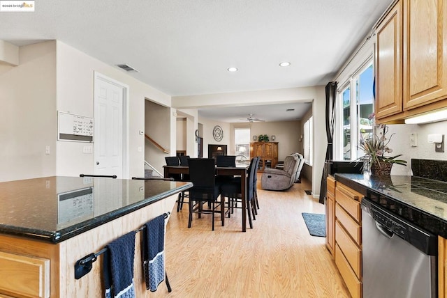 kitchen with ceiling fan, light wood-type flooring, stainless steel dishwasher, dark stone counters, and light brown cabinets