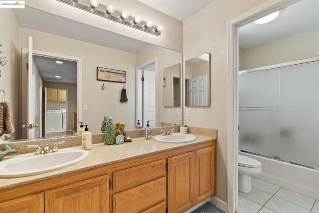 full bathroom with bath / shower combo with glass door, washer and dryer, vanity, toilet, and tile patterned floors