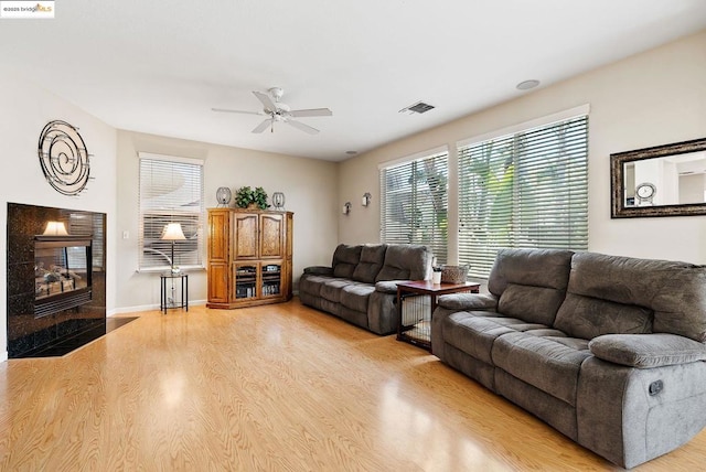 living room with a tile fireplace, ceiling fan, and light hardwood / wood-style flooring