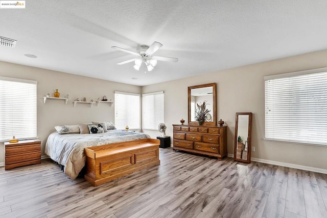 bedroom with multiple windows, ceiling fan, a textured ceiling, and light hardwood / wood-style flooring