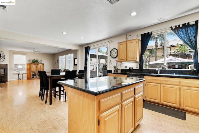 kitchen featuring ceiling fan, light brown cabinetry, a center island, and light hardwood / wood-style floors