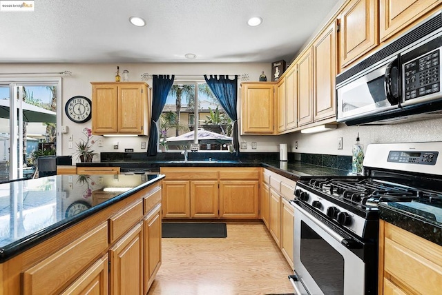 kitchen with sink, gas range, plenty of natural light, and light brown cabinets