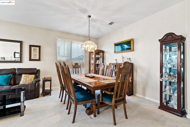 carpeted dining space with an inviting chandelier