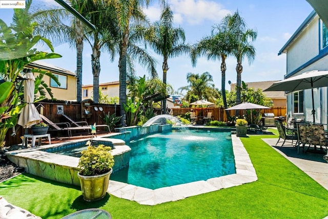 view of pool with pool water feature and a yard