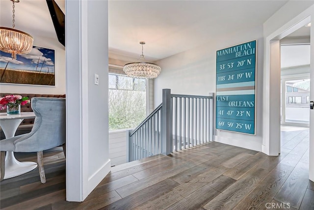 hall featuring dark wood-type flooring and an inviting chandelier