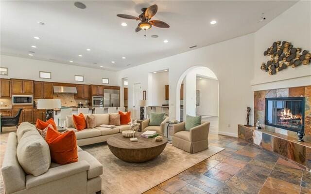 living room with a high end fireplace and ceiling fan