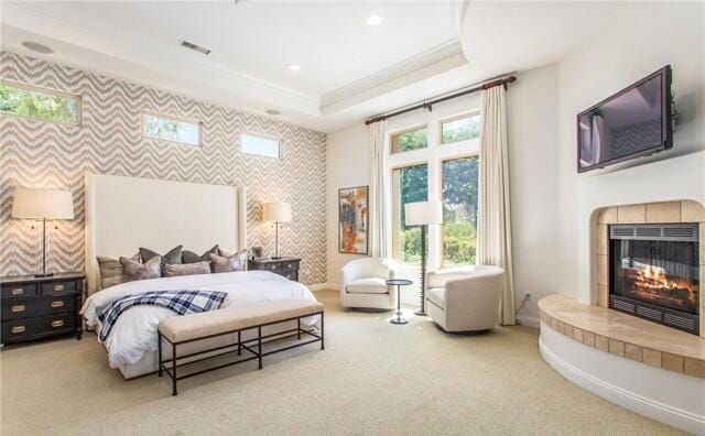 carpeted bedroom with a fireplace and a raised ceiling