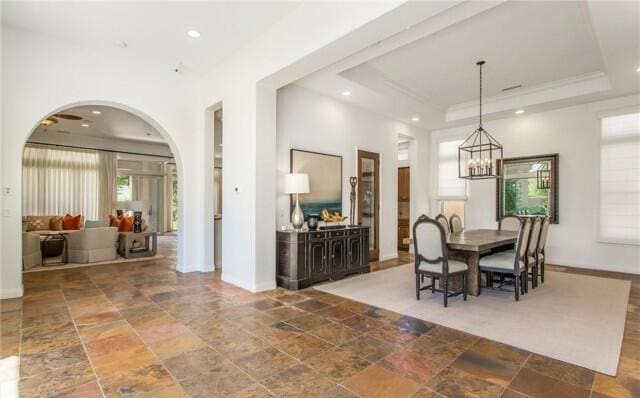 dining area with an inviting chandelier and a tray ceiling