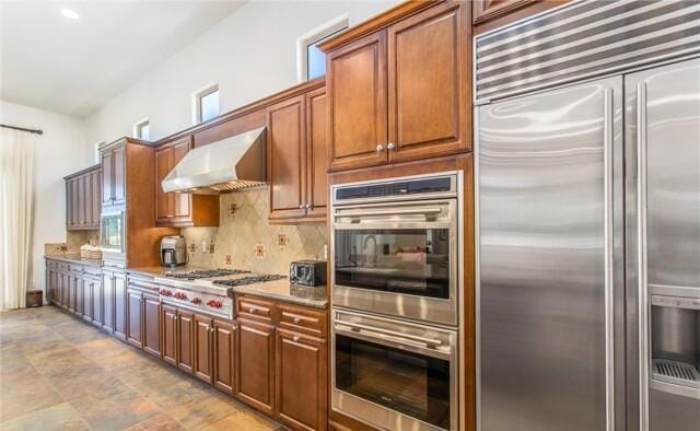 kitchen with stainless steel appliances, extractor fan, and tasteful backsplash