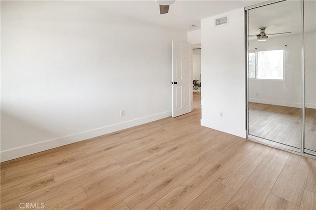 unfurnished bedroom featuring ceiling fan, light wood-type flooring, and a closet