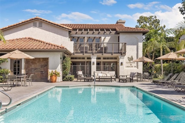 back of property with a community pool, a patio, and a balcony