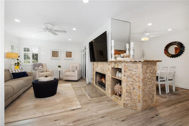 living room featuring ceiling fan, a fireplace, and light hardwood / wood-style flooring