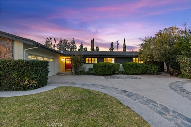 ranch-style house featuring a garage and a lawn