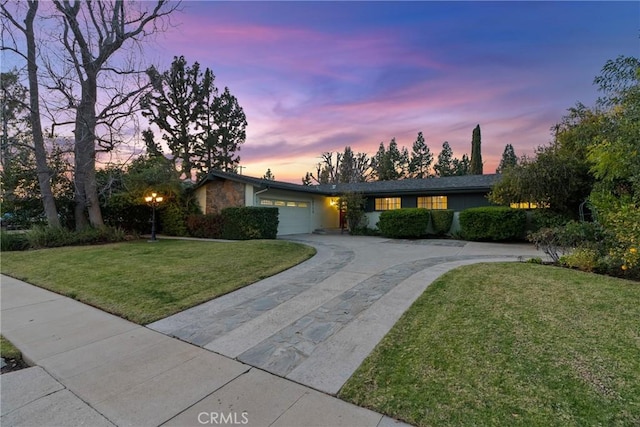 ranch-style home featuring a garage and a lawn