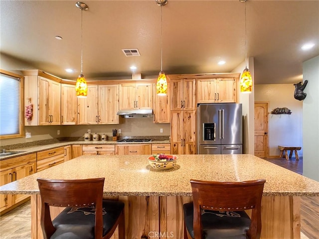 kitchen with stainless steel appliances, a kitchen island, and decorative light fixtures