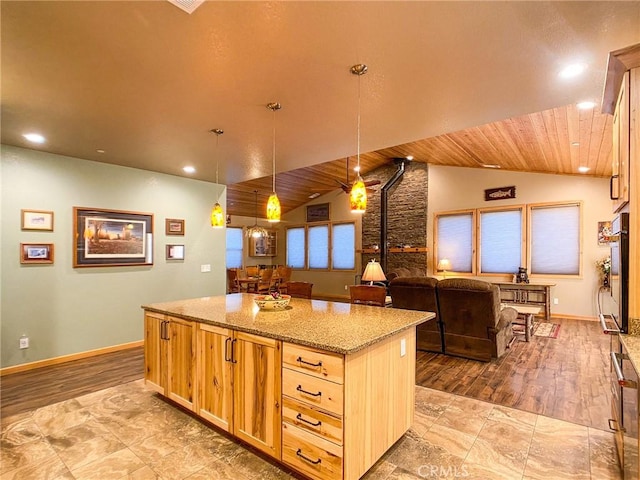 kitchen with lofted ceiling, light stone counters, a kitchen island, light brown cabinetry, and decorative light fixtures