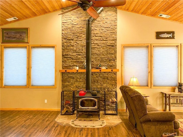 living room featuring vaulted ceiling, hardwood / wood-style floors, a wood stove, ceiling fan, and wooden ceiling